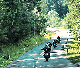 Motorradfahrer auf Landstraße durch Wald